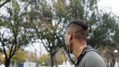 feliz, corriendo y escuchando música con un hombre negro en el parque