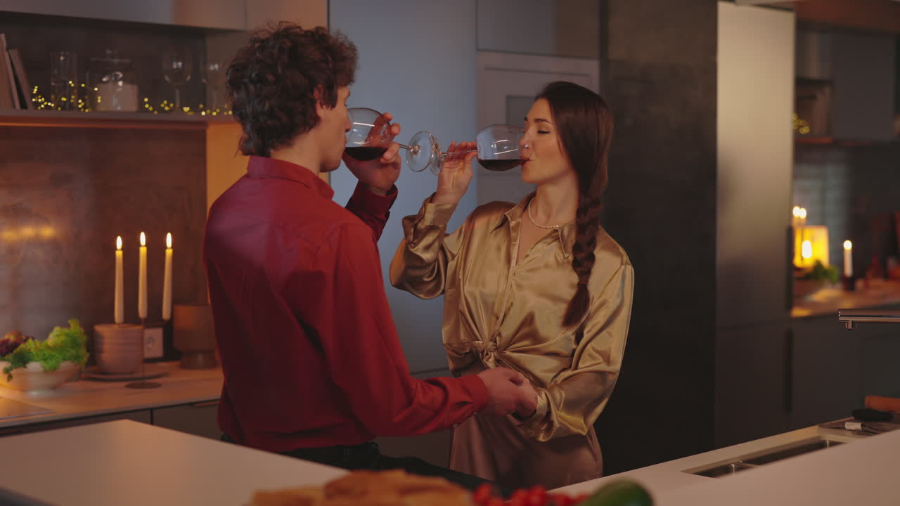 Coppia che si gode del vino rosso in una cucina accogliente.