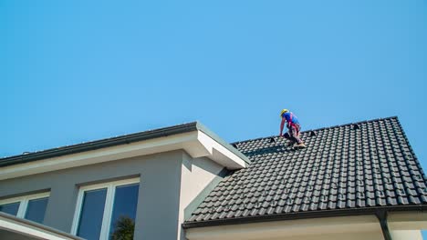 jonge mannelijke dakdekker loopt horizontaal van de ene kant van het dak naar de andere kant