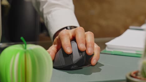 cerca de la mano de un hombre desplazándose con un ratón de computadora inalámbrica