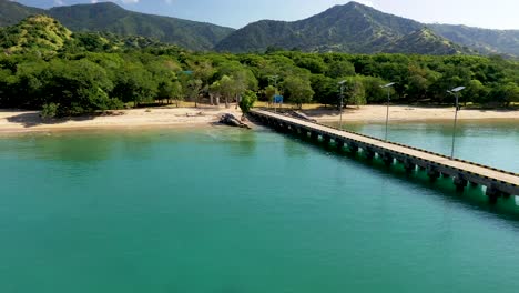 Pier-at-Loh-Liang-park-in-Komodo-island-Indonesia-which-is-used-as-an-access-point-for-ships-and-tourists-to-see-the-dragons,-Aerial-flyover-shot