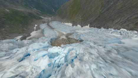 vuelo aéreo cinemático cuesta abajo sobre iceberg agrietado y derritiéndose en la montaña