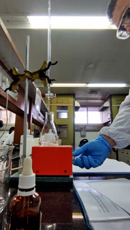 a man in a lab coat is wearing gloves and goggles as he works with a beaker