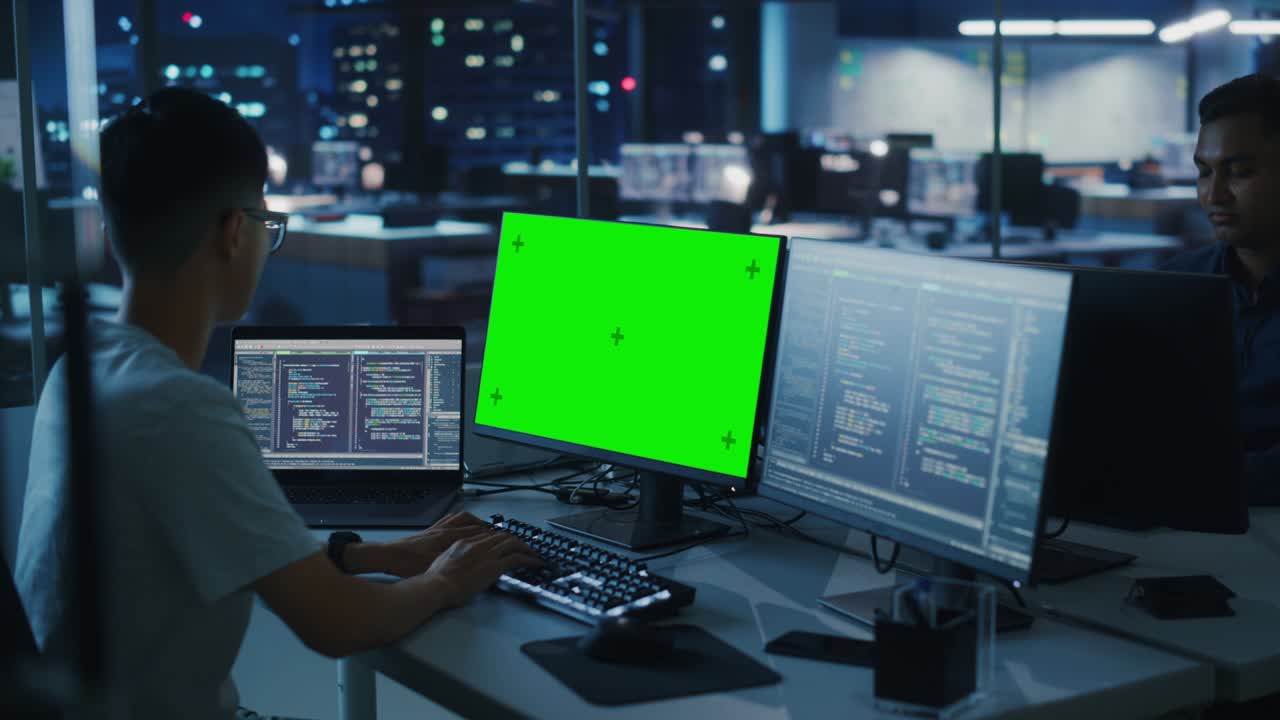 oficina nocturna: joven japonés trabajando en una computadora de escritorio de pantalla verde. equipo de programadores escribiendo código, creando software moderno, diseño de aplicaciones de comercio electrónico, programación de negocios electrónicos