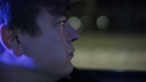 slow motion close up of young handsome businessman looking outside during traveling in a modern car with a driver in center of the city by the night. city lights