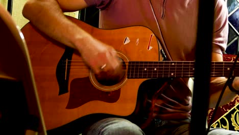 músico guitarrista rasgueando cuerdas en un pequeño bar local