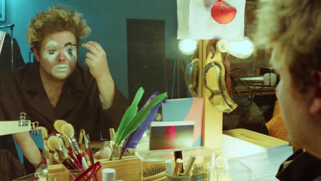 actor applying clown makeup in dressing room