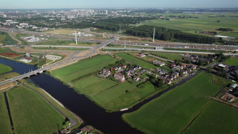 Vista-Aérea-De-Campos-Verdes-Y-Pueblo-Holandés-Junto-Al-Canal-Del-Río-Cerca-Del-Molino-Doesmolen-En-Hoogmade,-Países-Bajos