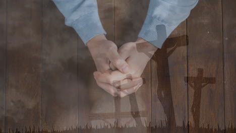 Praying hands over crucifixion animation on wooden background