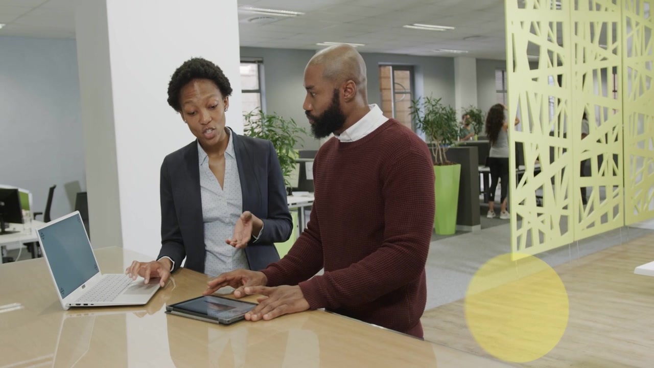 Woman pointing laptop and man tapping tablet causing circles showing tech data, obscuring, clearing