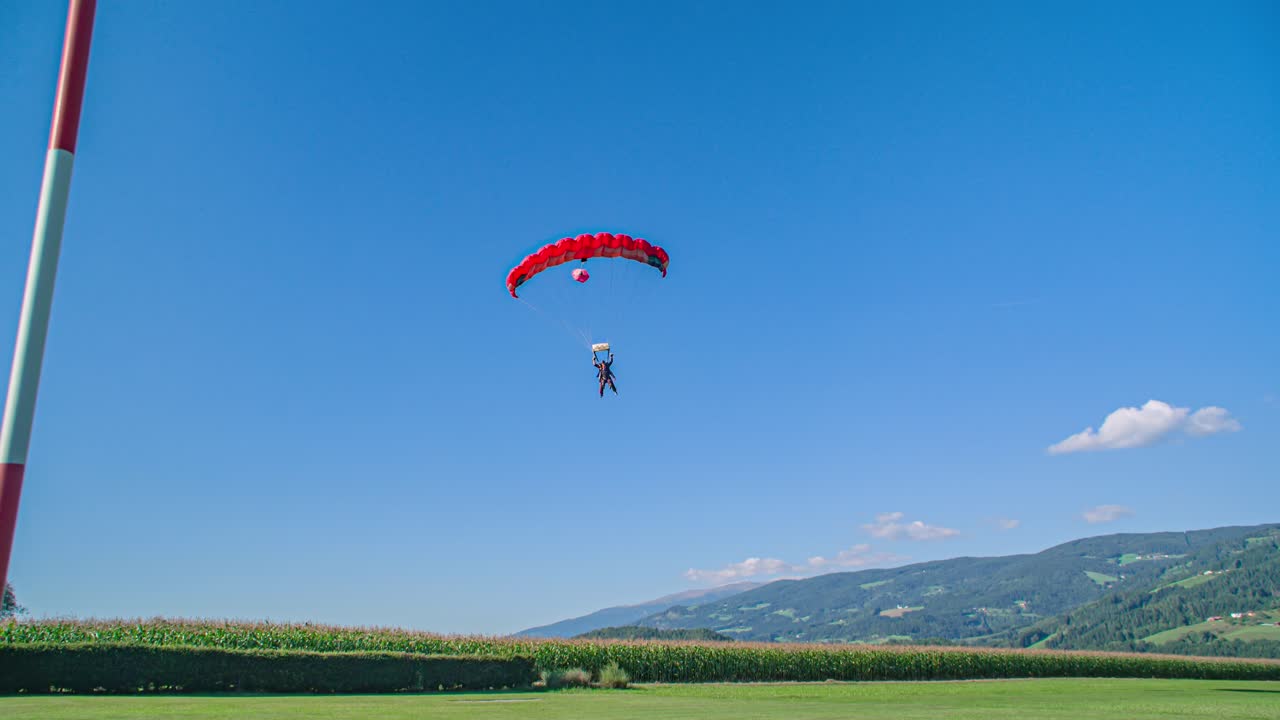 Instructor and student, tandem skydive landing. Windsock shows wind direction