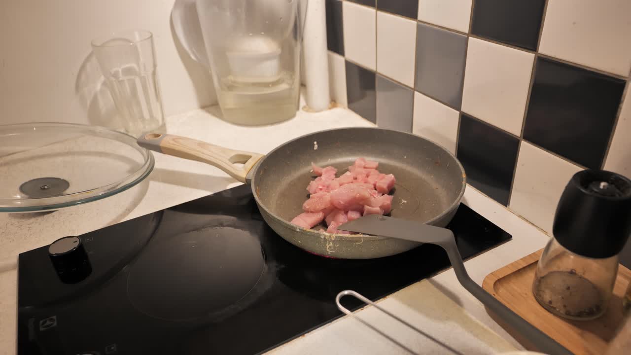 Diced turkey fillet being poured from cutting board into a hot pan for cooking.