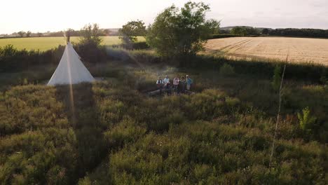 Drohnenaufnahme-Von-Reifen-Freunden,-Die-Auf-Dem-Campingplatz-Im-Freien-Am-Feuer-Stehen-Und-Lieder-Singen