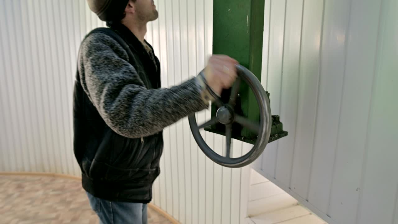 un investigador masculino gira la rueda manual del mecanismo de apertura de las puertas de la cúpula de un observatorio solar. estación de observación de investigación científica en las montañas del cáucaso