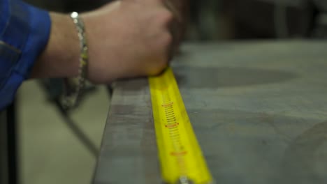 crop faceless woodworker measuring wooden board with ruler