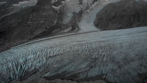 aerial view of the gauli glacier in the bernese oberland region of the swiss alps with a panning view from the crevasses at the glaciers end towards the mountain peaks