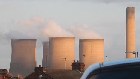 industrial cooling tower power station chimneys smoking steam pollution, close up above residential property rooftops.