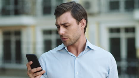 portrait man using smartphone outdoor. man typing on cellphone at street