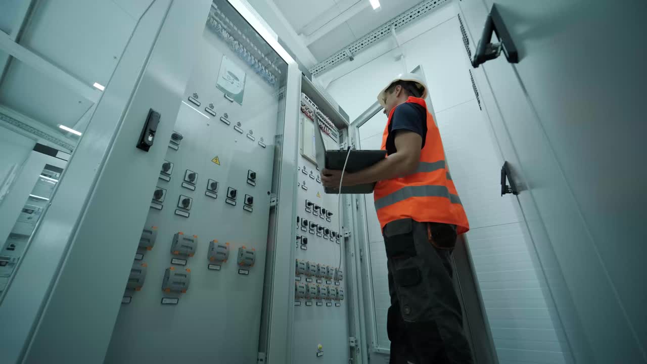 el ingeniero eléctrico que trabaja comprueba la tensión de corriente eléctrica y la sobrecarga en la parte delantera del gabinete del centro de carga o de la unidad de consumo para el mantenimiento en la sala principal del sistema de distribución de energía.