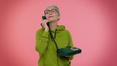 Senior-granny-gray-haired-woman-talking-on-wired-vintage-telephone-of-80s,-says-hey-you-call-me-back