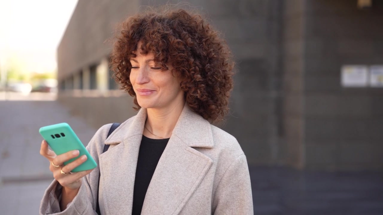 Una giovane donna che usa il suo smartphone all'aperto in un contesto urbano moderno, mostrando uno stile di vita.