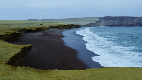 long wave crashes along playa de rojas shoreline with scenic coastal terrain visible, slow motion establishing static
