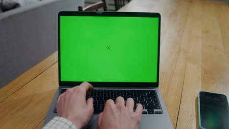 person working on a laptop with a green screen