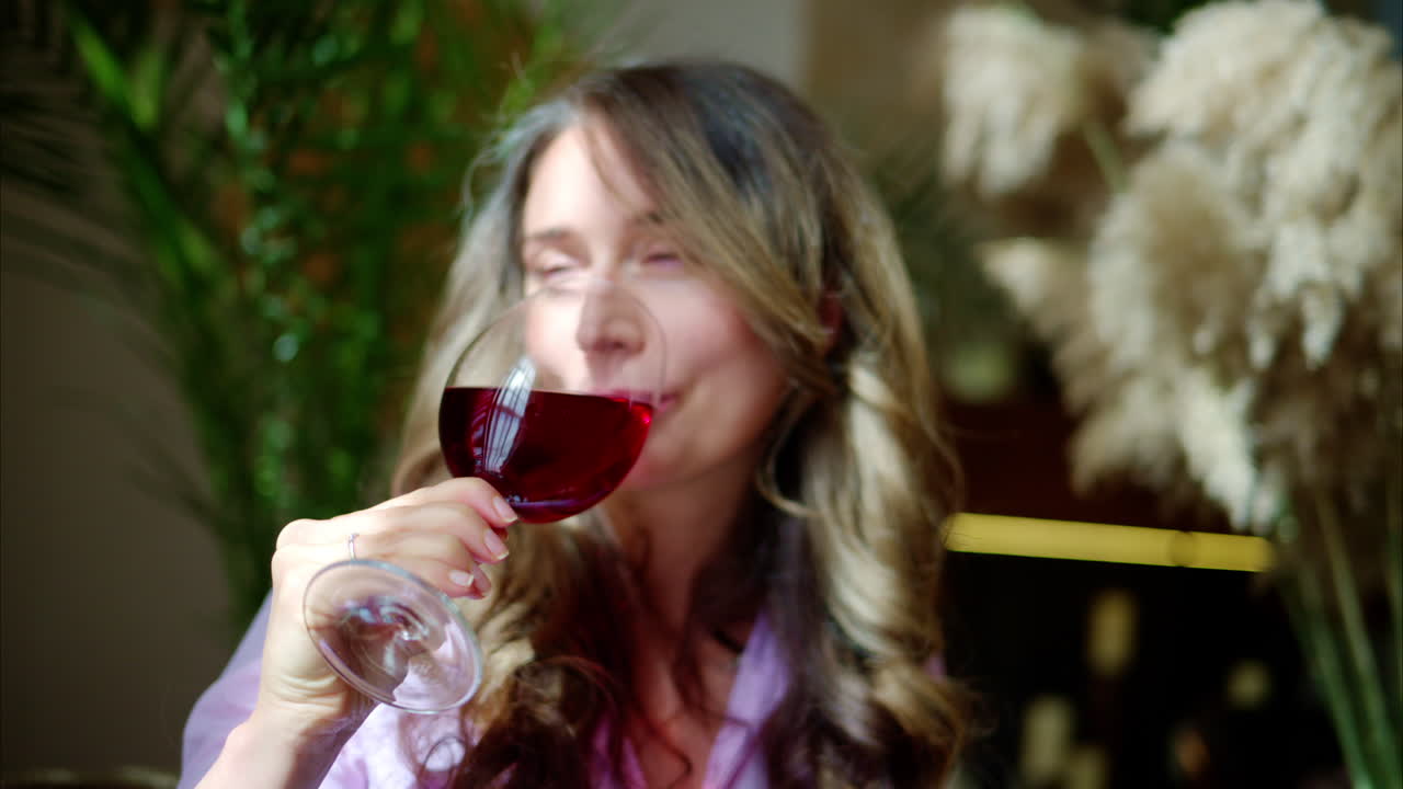 Close-up of woman savouring a glass of red wine in daylight