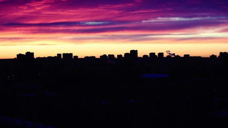Céu colorido ao amanhecer sobre a silhueta do horizonte da cidade