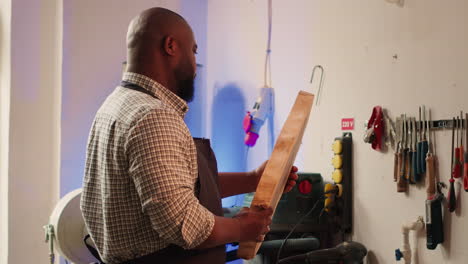 portrait of smiling carpenter in woodworking shop inspecting wood block