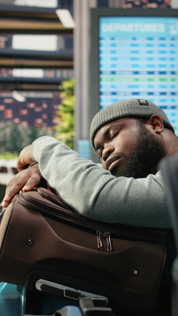 Viaggiatore stanco che dorme sui bagagli nel terminal dell'aeroporto