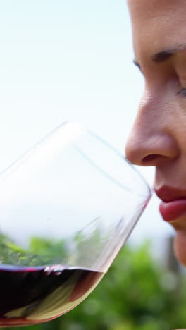 un primer plano de una mujer bebiendo un vino tinto
