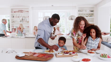 Familia-Y-Amigos-De-Varias-Generaciones-Reunidos-En-La-Cocina-Para-La-Fiesta-De-Celebración