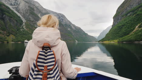 a woman is standing on the bow of the ship looking through binoculars cruise on the fjords of norway