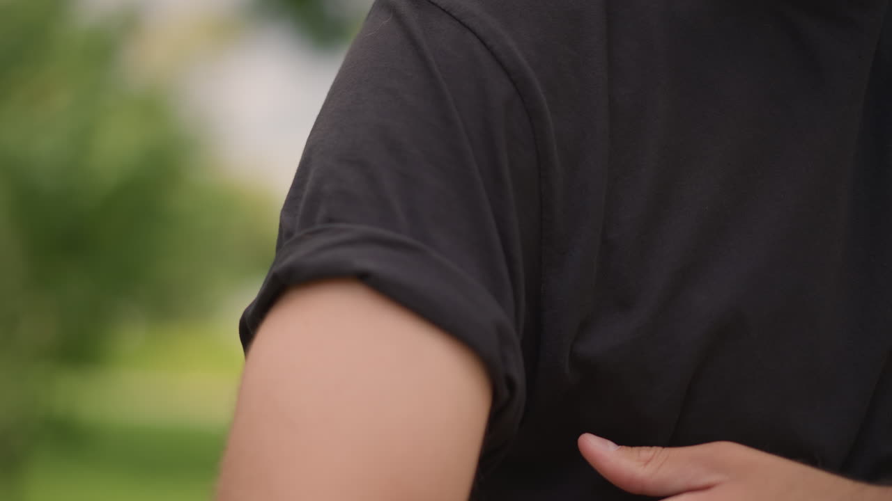 Caucasian Male Preparing For Workout In Park, Man Rolling Up Sleeve To Exercise In Sunny Park Setting, Closeup Of Man Adjusting Shirt Sleeve Before Engaging In Physical Activity Outdoors