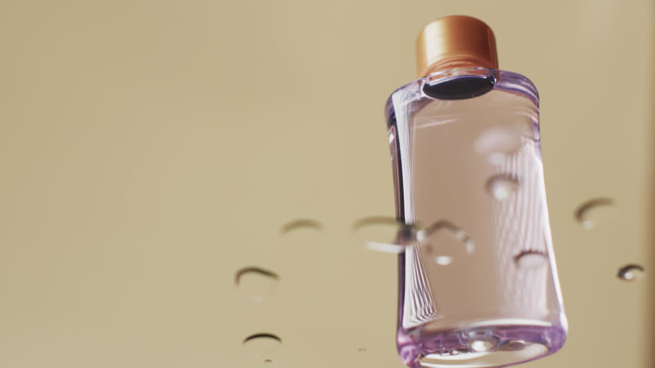 video de una botella de producto de belleza en agua con espacio de copia en fondo amarillo