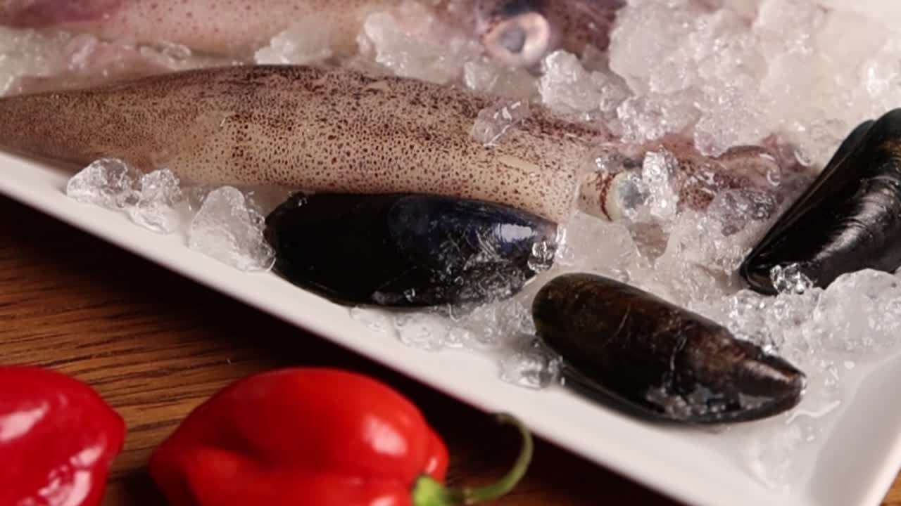 Frischer roher Tintenfisch und Muscheln auf Eis mit rotem Paprika