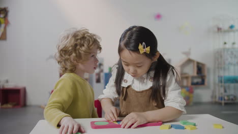 petite fille et petit garçon jouant avec le puzzle de l'alphabet à l'école montessori 1