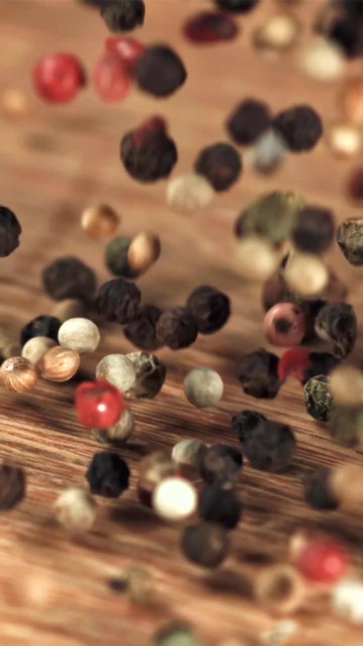 Mixed Peppercorns Falling and Bouncing on a Wooden Surface