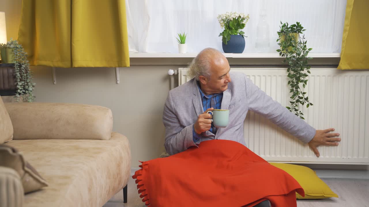 Den gamle mand, der drikker kaffe og læner sig op ad radiatoren, fryser.