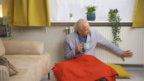 The-old-man-drinking-coffee-leaning-against-the-heater-is-cold.