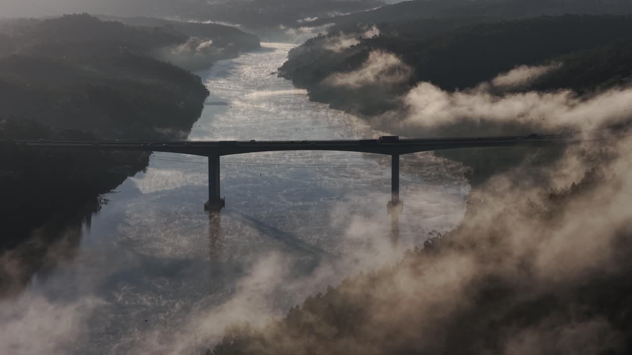Morning mist in the river with cars driving across the bridge drone flying forward