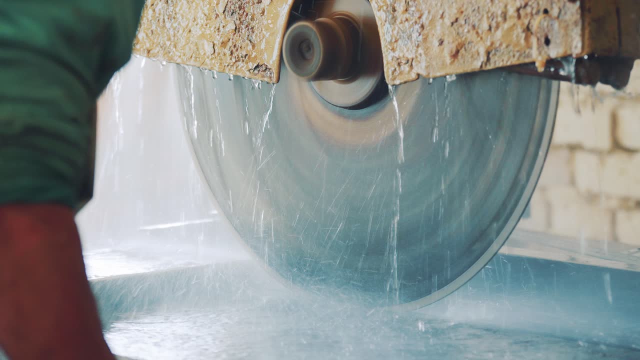 Cutting a stone slab of sandstone with a circular saw on a machine tool. Jet and spray of water in the stone processing industry