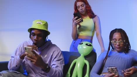 fotografía de estudio de amigos jóvenes de la generación z sentados en el sofá compartiendo publicaciones en las redes sociales en teléfonos móviles 2