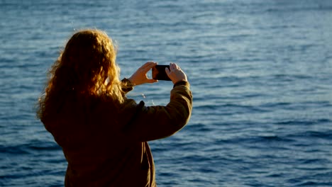 mujer haciendo clic en fotos con teléfono móvil en el muelle 4k