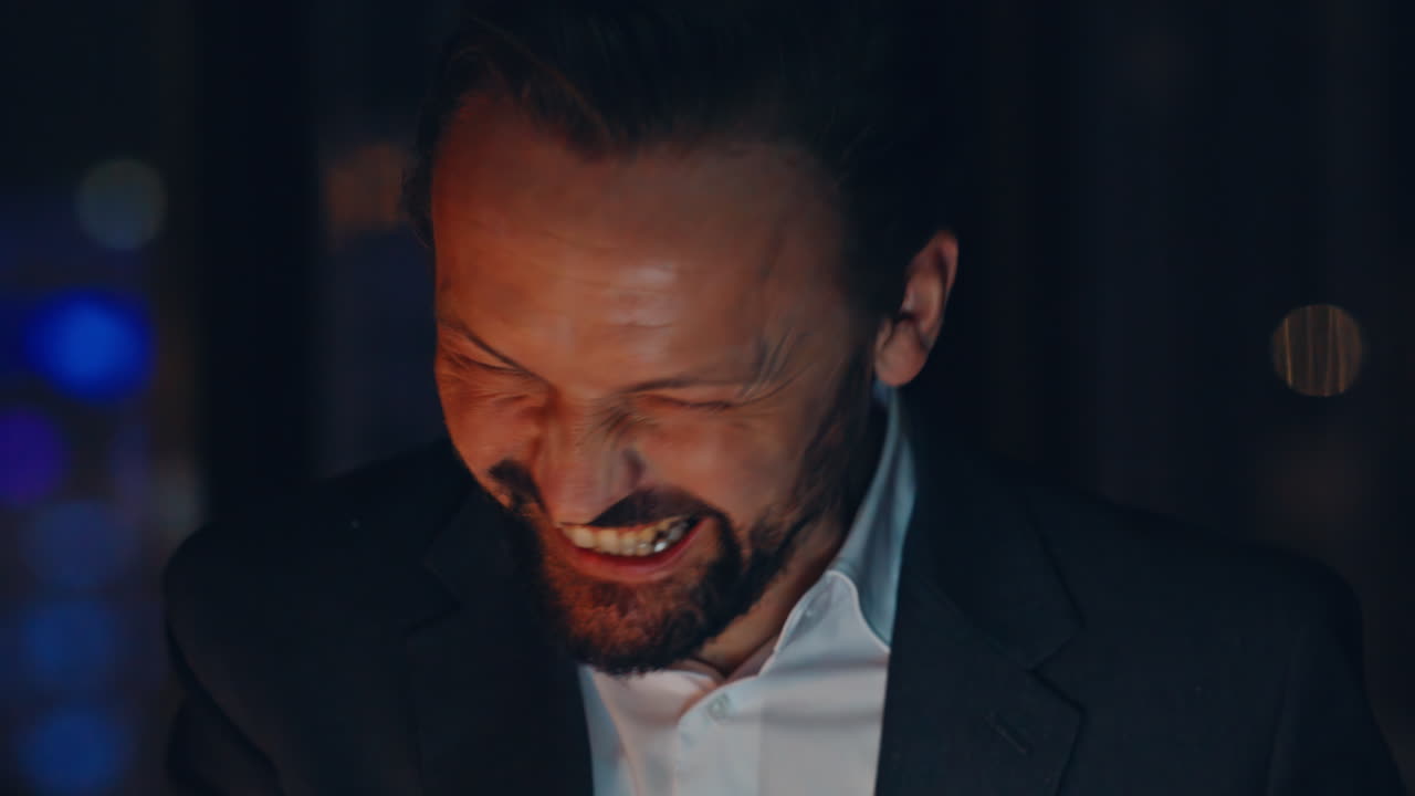 Ritratto di un allegro regista che fa una videochiamata in un ufficio buio. Uomo sorridente che parla