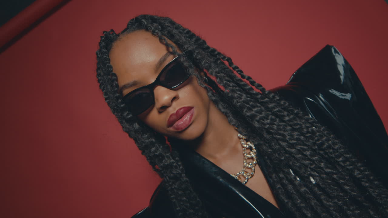 una foto al revés de una chica modelo confiada posando con una bola de vidrio redondeada en el estudio