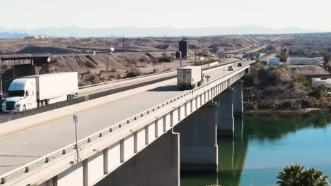 cars and trucks driving over bridge, river below, drone follow shot, close up, border between california and arizona , colorado river , i-40 freeway east