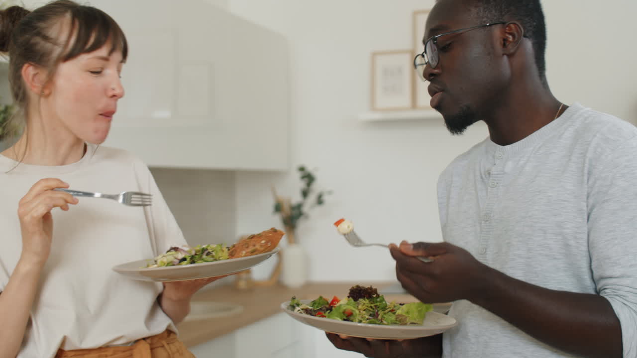 una pareja joven y diversa comiendo ensalada y hablando