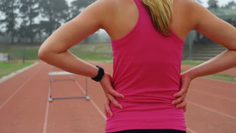 vista trasera de una atleta de pie con las manos en la cadera en una pista de carreras 4k